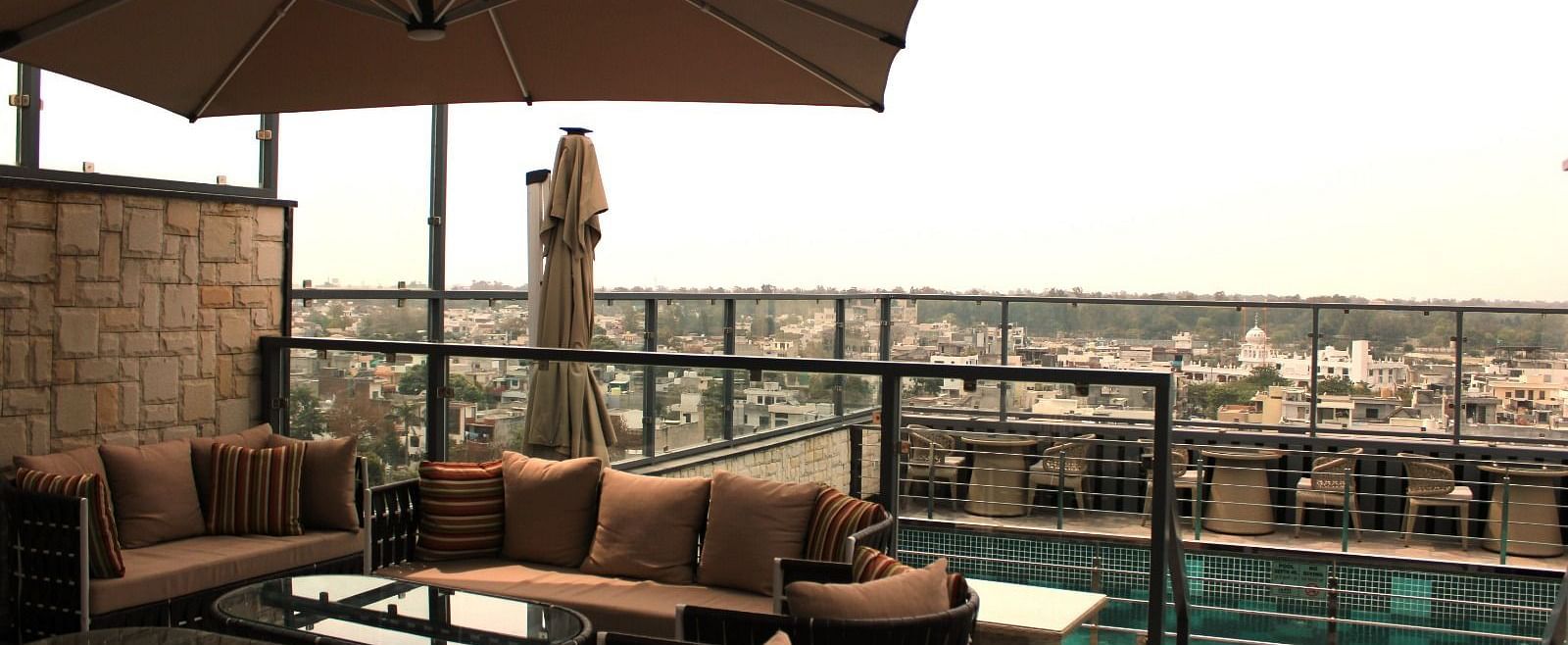 A rooftop lounge with a spacious patio and an adjacent swimming pool at BluSalzz Residence, Amritsar